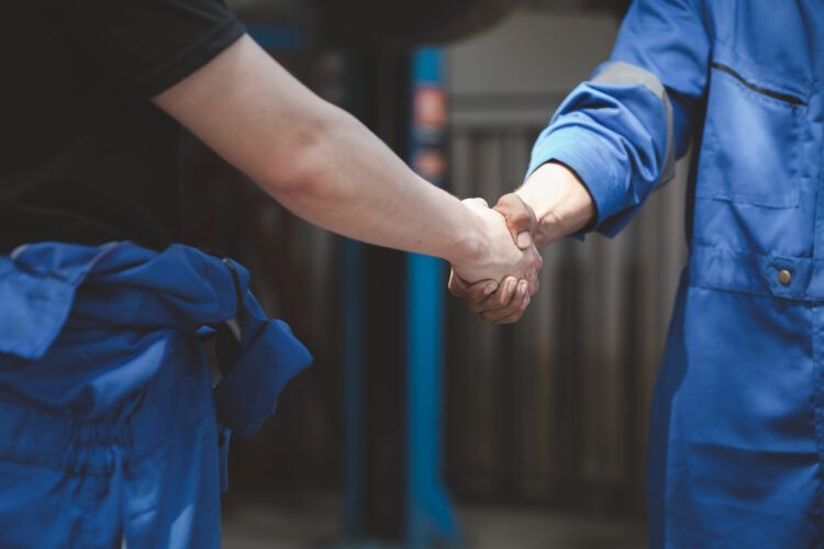 two mechanics shaking hands.
